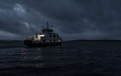 A small touring boat sailing at the night with cloudy dark sky