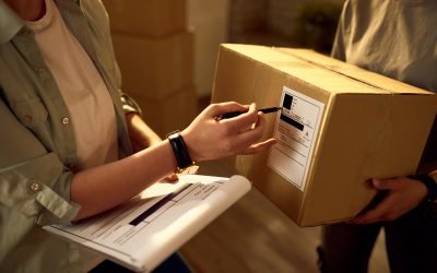 Two delivery women cooperating while checking data on the packages in the office.